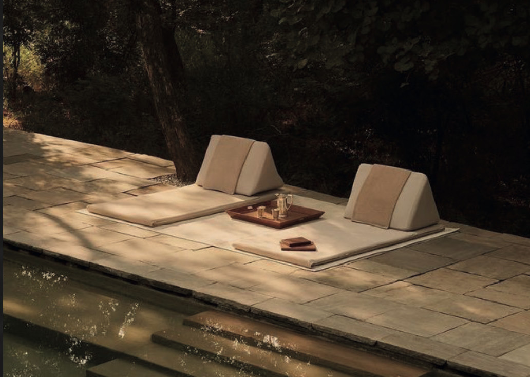 Matelas de détente au bord d'une piscine en pierre, à l'ombre des arbres