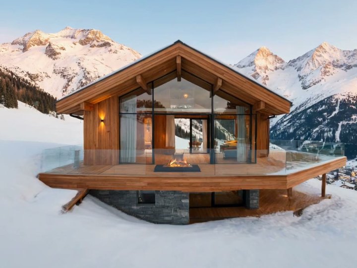 Chalet en bois aux grandes baies vitrées face aux montagnes enneigées